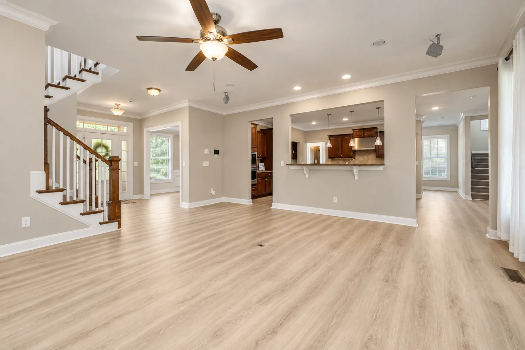 Open interior with light wood-look flooring, staircase and kitchen